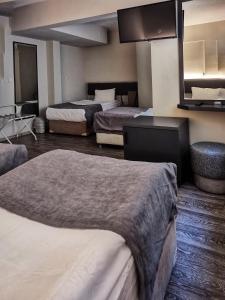 Habitación de hotel con 3 camas y espejo en Temizay Hotel, en Canakkale