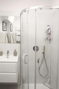 La salle de bains blanche est pourvue d'une douche et d'un lavabo. dans l'établissement Przy Brzegu - Hel studio, à Hel