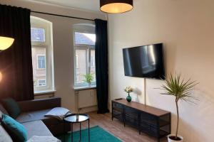 ein Wohnzimmer mit einem Sofa und einem TV an der Wand in der Unterkunft Holiday apartment in Leipzig