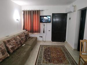 sala de estar con sofá, TV y puerta en Chalet at Stella Di Mare Makadi Bay en Hurghada