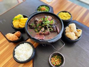 a table with a bowl of food and bowls of rice at Hotel Senac Ilha do Boi in Vitória