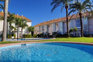 a swimming pool in front of a building with palm trees at Golden Gardens Lux apartment Jávea in Jávea
