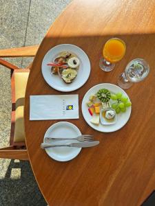 a table with two plates of food and glasses of orange juice at Hotel Senac Ilha do Boi in Vitória