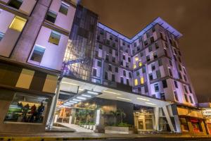 聖何塞的住宿－Urban Green Hotel & Suites，一座建筑,在晚上前有商店