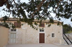 un edificio de piedra con una puerta y un árbol en Il Carrubo Holiday House, en Scicli