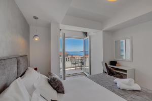 a white bedroom with a bed and a balcony at Apartments Dany in Makarska