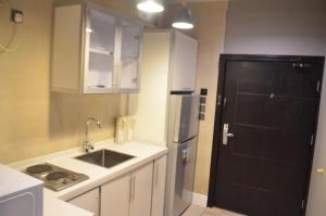 eine Küche mit einer Spüle und einem schwarzen Kühlschrank in der Unterkunft هوم للأجنحة الفندقية in Chamis Muschait