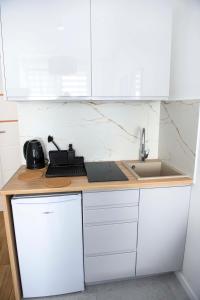 - une cuisine blanche avec évier et comptoir dans l'établissement Przy Brzegu - Hel studio, à Hel