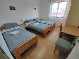 two beds in a room with a table and a chair at Soko-Veljkovic-apartman in Soko Banja