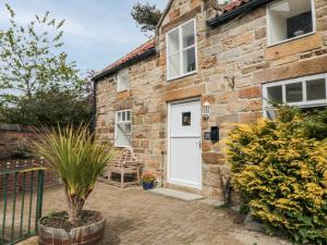 Casa de piedra con puerta blanca y patio en St Hilda's Cottage, en Hinderwell