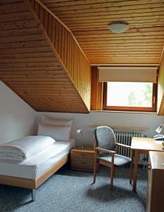 a bedroom with a bed and a desk and a chair at Waldgasthof zum Geländer in Eichstätt