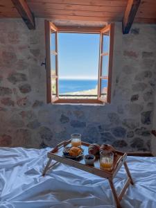 a tray of food sitting on a bed with a window at Roots Dhermi in Dhërmi