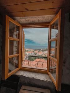 een open raam met uitzicht op de oceaan bij Roots Dhermi in Dhërmi