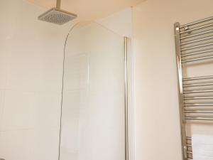 a shower with a glass door in a bathroom at Sleeper Cottage in Filey +4 photos