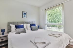 1 dormitorio blanco con 1 cama grande con almohadas azules en 3 Bed Private Bungalow Close to Amenities, Wifi, Parking by Ark SA en Sheffield