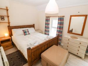a bedroom with a bed and a mirror and a dresser at Glascoed in Pwllheli