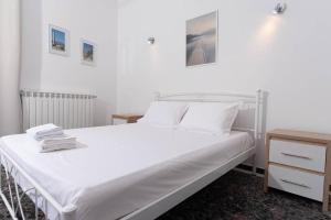 a white bedroom with a white bed and a nightstand at Modern apartment 1 minute from Remataki beach in Samos