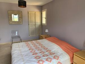 ein Schlafzimmer mit einem Bett mit einer orangen und weißen Bettdecke in der Unterkunft Le mas christine in Buis-les-Baronnies