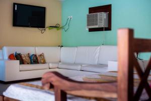 a living room with a white couch and a tv at Praia e Mar Angra in Angra dos Reis