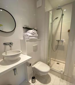 een badkamer met een douche, een toilet en een wastafel bij Hôtel Les Bains in Saint-Valéry-en-Caux