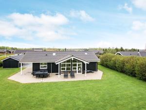 a black house with a deck and a large yard at Three-Bedroom Holiday home in Hemmet 74 in Falen
