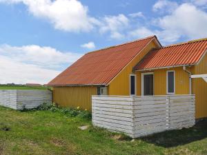 una casa amarilla con techo rojo y valla en 5 person holiday home in Lemvig, en Lemvig