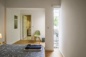 a bedroom with a bed and a green chair at Thalassa Villas in Ponta Delgada