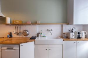 cocina con armarios blancos y fregadero blanco en La maison d'à côté 3 - 6 people - 3 bedrooms - 2 bathrooms en Honfleur