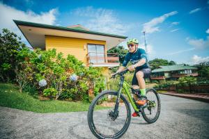 un homme faisant du vélo devant une maison dans l'établissement Hotel Ficus - Monteverde, à Monteverde Costa Rica