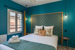 um quarto com paredes azuis e uma cama com almofadas em Vert d'Hotes - Charming renovated apartment - downtown - WIFI - em Honfleur