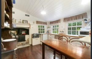 a large kitchen with a table and a fireplace at Jacomb's Cottage and Studio in Walhalla