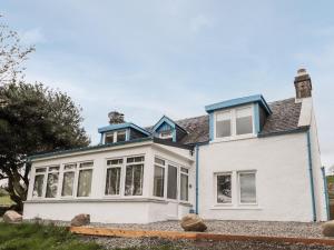 a white house with a blue roof at Balnaird Farmhouse in Strathpeffer
