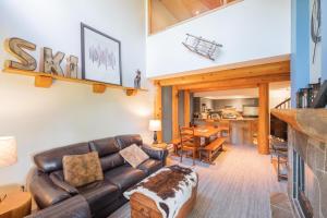 a living room with a leather couch and a table at Powderhorn by Outpost Whistler in Whistler