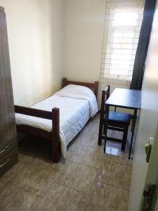 1 dormitorio con cama, escritorio y mesa en Hotel Veritas en Guarapuava