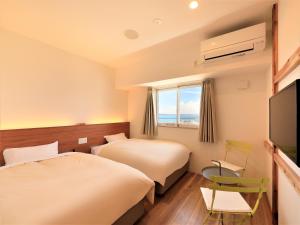 a hotel room with two beds and a flat screen tv at Central Resort Miyakojima in Miyako-jima
