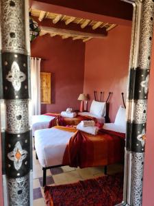 two beds in a room with red walls and a mirror at Chez Laila in Skoura
