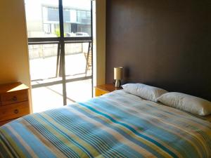 1 cama en un dormitorio con ventana grande en Puka Bach - Matarangi Holiday Home, en Matarangi