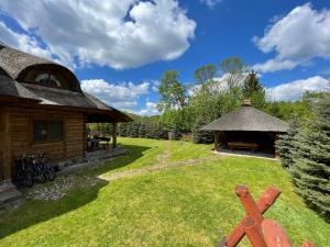 a cabin with a thatch roof and a grass yard at Willa Pod Strzechą in Wiartel Mały