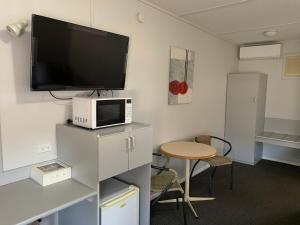 sala de estar con TV, mesa y sidx de mesa en Orana Windmill Motel, en Gilgandra