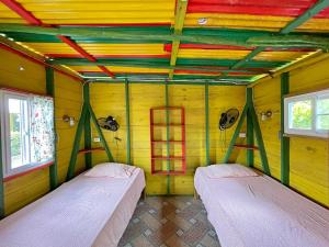 two beds in the corner of a room with yellow walls at Judy House Two in Little Bay