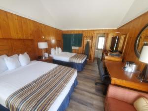 a room with two beds and a desk and a television at Bayview Lakefront Inn in Saint Ignace