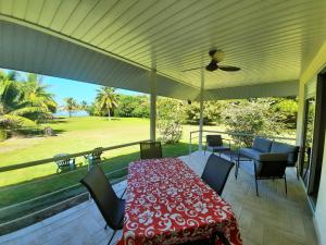 a covered patio with a table and chairs and a field at Résidence Apaura in Vaianae