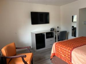 a hotel room with a bed and a flat screen tv at Redwood Inn in Santa Rosa