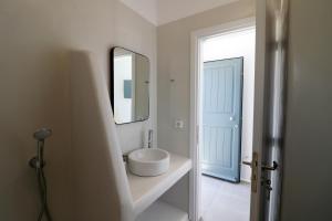 a white bathroom with a sink and a mirror at Archon Seaside Retreat in Plaka