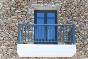 a window with a blue railing on a stone wall at Archon Seaside Retreat in Plaka