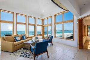 a living room with a couch and chairs and windows at Luxury Beachfront Penthouse Walk to the Beach Restaurants Entertainment in Half Moon Bay