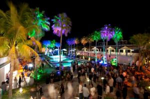 een menigte mensen die 's nachts rond een zwembad lopen bij Kimpton Surfcomber Hotel, an IHG Hotel in Miami Beach