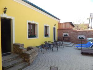 a patio with chairs and tables and a yellow building at Boros Vendégház II. in Kőszeg