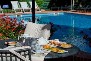 a table with plates of food next to a pool at Park Hotel Chianti in Tavarnelle Val di Pesa