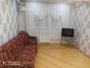 a living room with a couch and a television at 2х комнатная квартира со всеми удобствами in Sumqayyt